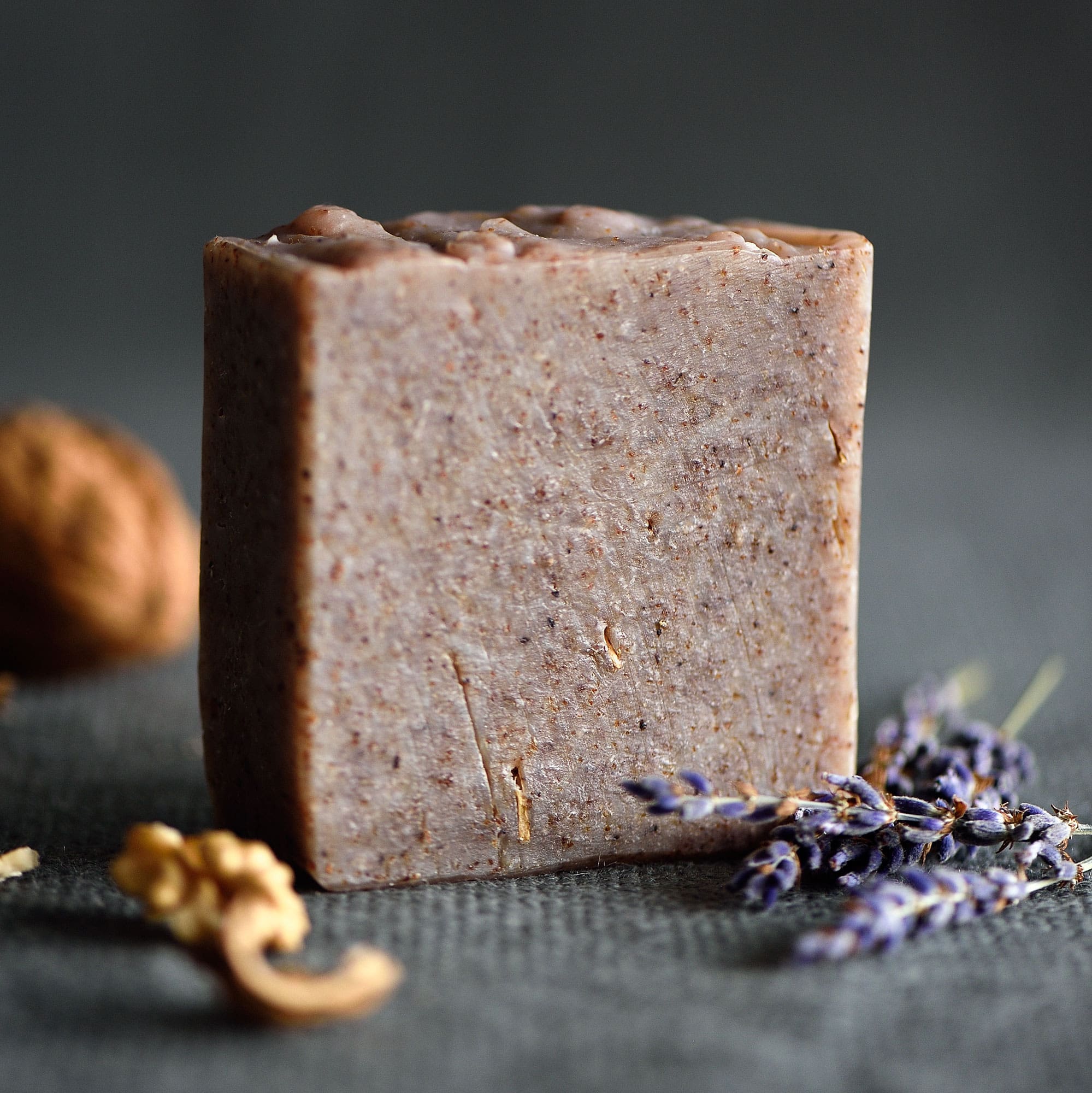 Handcrafted body soap bar displayed with fresh lavender and a walnut
